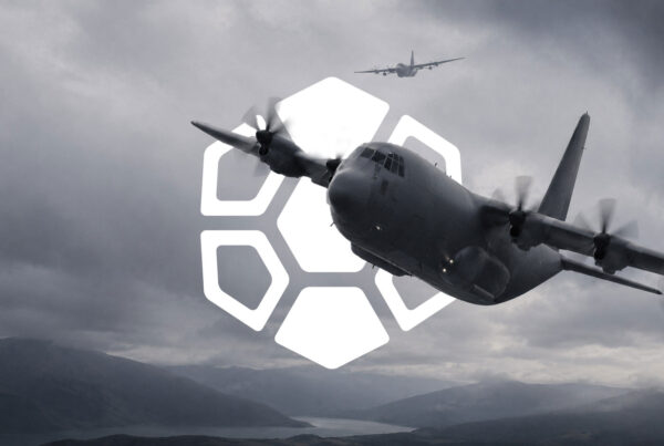 Military transport aircraft flying over mountainous terrain with the Diamondback Solutions geometric brand mark